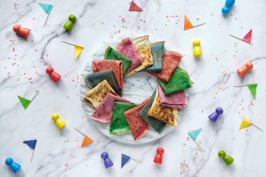 Gökkuşağı partisi, masa kurulumu. Canlı krepler, mermer masanın üzerinde tahta figürler ve kağıt bayraklarla krepler. Şefkat, dostluk, ayrıcalık ve LGBT gururunun sembolü olarak gökkuşağı. Yaratıcı parti yemekleri.