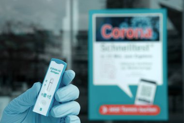 Berlin, Almanya - 11 Nisan 2021: Mitte 'de covid testleri için Coronavirus testi yapılan eldiven. Berlin 'de alışveriş için Schnelltest, Almanca hızlı corona testi gereklidir..