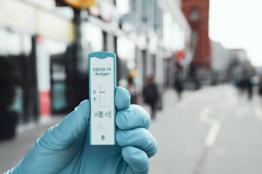 Alexanderplatz 'ın arka planında çeşitli dükkanlar bulunan COVID-19 testi. Schnelltest, Almanca hızlı corona testi, alışveriş için gereklidir.