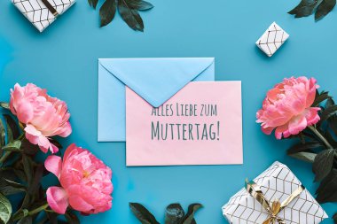 Alles Liebe zum Muttertag 'a mesaj at. Anneler Günü için çok sevgi demek. Pembe şakayık çiçekleri, yaprakları ve paketlenmiş hediye kutuları olan tebrik kartı tasarımı. Düz konum, üst görünüm, mavi nane kağıdında karşılama düzenlemesi.