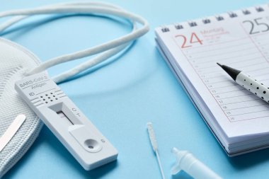 Haftanın planlayıcısı, Almanca hızlı korona testi. Hafta planlama takvimi ve nane mavisi masada pp2 tıbbi yüz maskesi. Deneme sürümü konsepti.