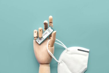 Tahta elde COVID 19 testi ve tıbbi maske. Schnelltest, hızlı korona testi, Selbsttest, kendini test demektir. Ekspres koronavirüs testi minimum konsept tasarım. Düz zemin, yeşil nane arkaplanı.