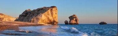 Afrodit, Kıbrıs Rum Kesimi 'ni yumuşak akşam ışığında sallıyor. Aşk kayası denen bu kayanın ön plandaki kıvrımlı dalgaları turistik açıdan çekici kılıyor.