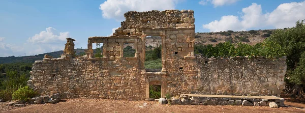 Girit adasının kırsal kesiminde, Akdeniz adasının doğu kesimindeki kırsal kesiminde eski bir antik manastırın terk edilmiş taştan kalıntıları. Bulutlu mavi gökyüzü.