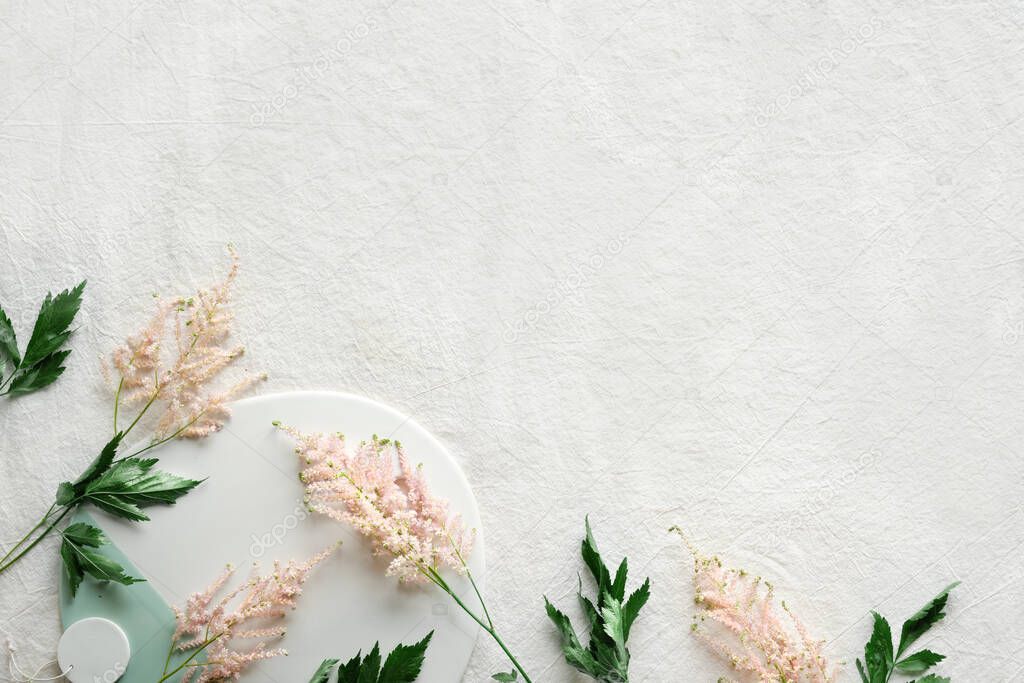 Natural Summer background with border of wild flowers. Copy-space, place for text. Flat lay on off white linen background with pale pink wild Prachtspiere, Astilbe flowers and green leaves.
