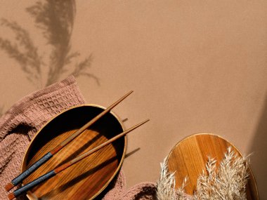 Öğle yemeği paketi. Kahverengi karton arka planda sıfır atık paketlenmiş beslenme çantası. Beslenme çantası, bambu çatal ve Furoshiki kumaşına sarılı kaşık. Düz uzanış, vahşi çimenlerin modaya uygun gölgeleri, metin alanı.