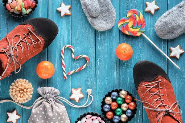 Saint Nicholas Day or Nikolaus Tag in German language. Traditional holiday in Germany and Western Europe. Various sweets, candy, cookies, satsuma and pair of shoes, flat lay on turquoise background.