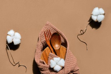 Beslenme çantası seti. Metin Sıfır Atık metni. Kahverengi kağıt arka planda basit bir düzenleme, pamuk çiçekleri. Beslenme çantası, ahşap kaşık ve çatal Furoshiki kumaşına sarılı..