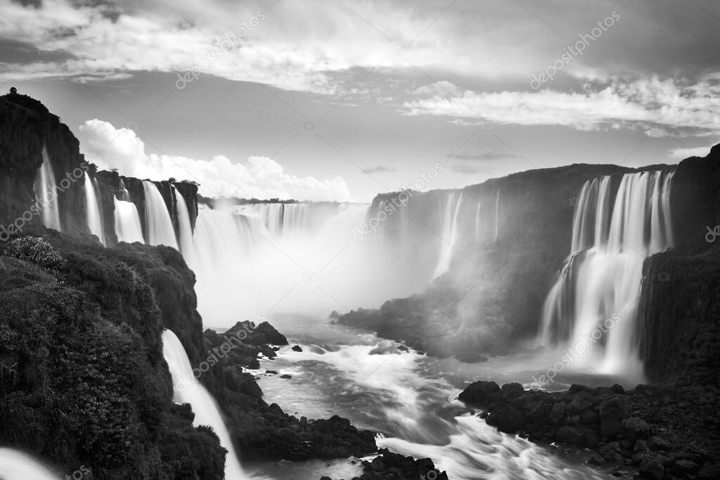 Iguazu waterfalls in Argentina, black white monochrome picture. View from Devil's Mouth. Majestic powerful water cascades with mist.
