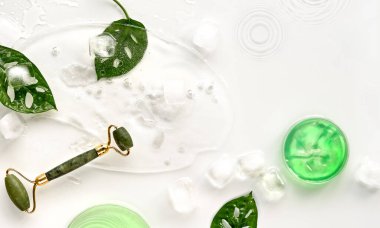 Buz küpleri ve egzotik yapraklarla buzda yüzen yeşil yeşim taşı. Monstera Adansonii İsviçre peyniri beyaz arka planda bırakır. Güzellik yüz masajı ve ev yapımı nemlendirici konsept düz..