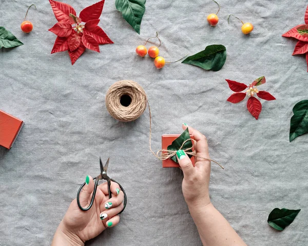 Weihnachtsflach Lag Auf Naturbeigem Leinenstoff Hände Schmücken Geschenkboxen Roter Weihnachtsstern — Stockfoto