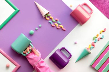 Geometrik kağıt üzerinde parti eşyalarının toplanması düzdü. Çikolata, şeker ve gökkuşağı lolipop girdabı. Seramik kahve kupaları. Geometrik katmanlı arka plan koyu mor, kırmızı, nane yeşili beyaz.