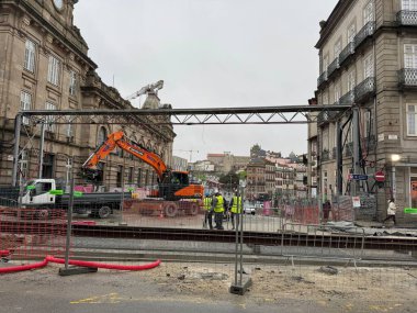 Porto, Portekiz - 16 Şubat 2026: Tarihi şehir merkezinde kazıcı ve ekipler bulutlu kış gökyüzü altında açık tramvay rayları, geçici eskrim ve trafik şaşırtmacalarının yanında çalışarak ulaşımı kısıtlayan belediye yol çalışmaları