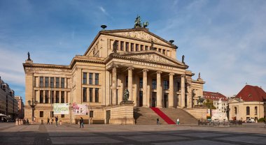 Berlin, Almanya 2 Ekim 2015: Yeşil bakır kuleye sahip tarihi tuğla kilise Berlin 'in orta kesiminde süs pınarı ve ağaçlarla kaplı yürüyüş yolunun yanında duruyor, açık mavi gökyüzü ve sonbahar yaprakları ön planda görünüyor.