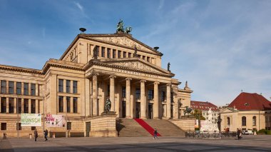 Berlin, Almanya 2 Ekim 2015: Gendarmenmarkt 'taki Fransız Katedrali açık mavi gökyüzünün altında sütunlu giriş ve kule, ziyaretçi ve bankların bulunduğu asfalt plazaya hakim.