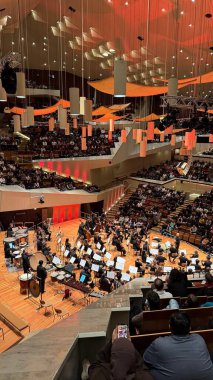 Berlin, Almanya - 15 Aralık 2025: Günümüz Filarmoni Orkestrası, katmanlı balkonları ve aydınlatılmış akustik tepe örtüsüyle modern Filarmoni Berlin konser salonunda performans sergiliyor.