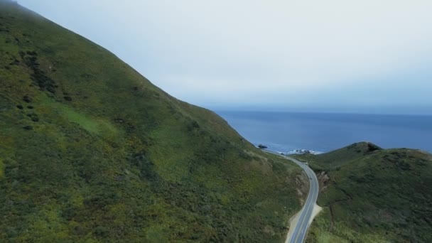 カリフォルニア州ガラパタの海の近くの緑の丘を行く道路の空中撮影 — ストック動画