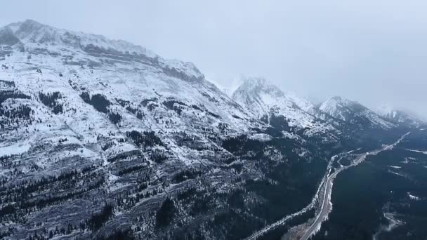 カナナスキス,アルバータ州,カナダの雪に覆われた冬の黒と白の山の斜面のドローン撮影 — ストック動画