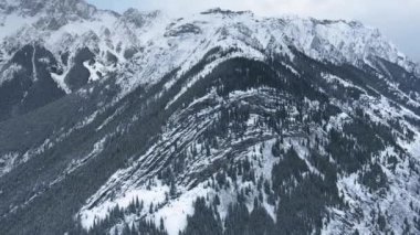 İnsansız hava aracı Kananaskis, Alberta, Kanada 'da buzlu havada siyah beyaz kayalardan oluşan karlı zirveler vuruyor.