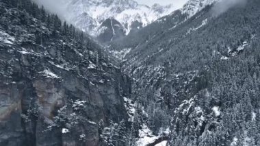 İnsansız hava aracı Kananaskis, Alberta, Kanada 'daki vahşi ormanlarda karlı kayaların üzerinden uçuyor.
