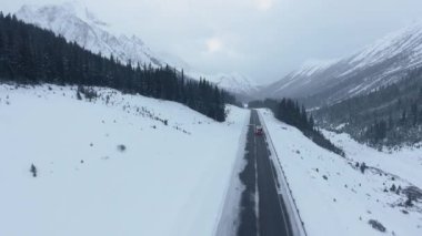 Kananaskis, Alberta, Kanada 'da kış ortasında dağın eteklerinden geçen yüksek bir yerden havadan görüntüler.