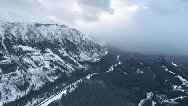 Fotocamera aerea che cattura pesanti nuvole invernali che scendono nella valle nera nel gelo a Kananaskis, Alberta, Canada — Video Stock
