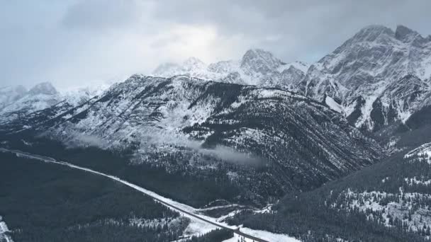 Video aereo di splendida natura invernale: montagne innevate, foresta ghiacciata e pesanti nuvole grigie a Kananaskis, Alberta, Canada — Video Stock