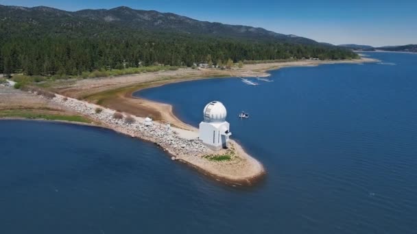 ドローンはビッグベア太陽観測所、水平線の湖の空中ビュー、カリフォルニア州ビッグベア湖の鬱蒼とした森と山の周りをスムーズに移動します。 — ストック動画