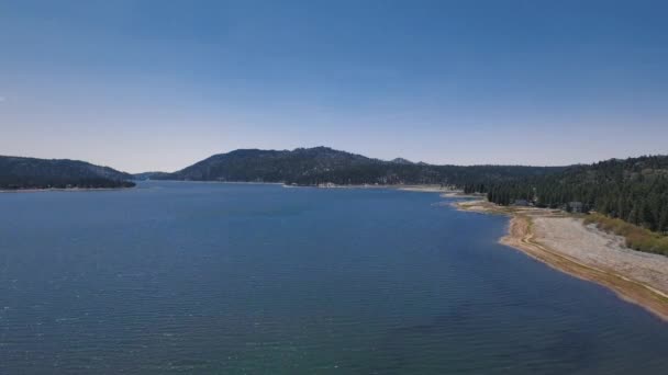 Drone se aleja de la montaña, el bosque y el observatorio solar Big Bear en un día despejado, vista aérea del lago Big Bear, California, EE.UU. — Vídeo de stock