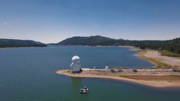 Imágenes de drones del observatorio Big Bear Solar en un lago tranquilo, montañas y bosques visibles, vista aérea del lago Big Bear, California, EE.UU. — Vídeo de stock