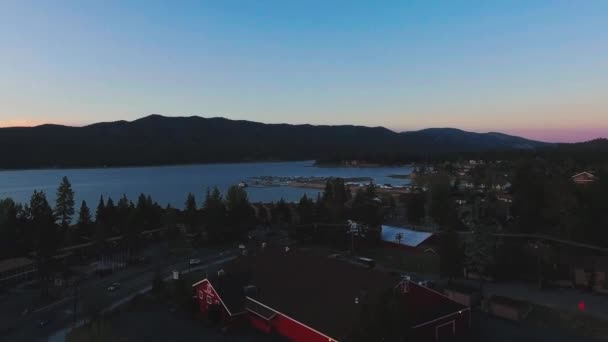Drone se pohybuje po střechách domů, auta jet podél silnice k jezeru poblíž Big Bear Solar observatoře, letecký pohled na Big Bear Lake, Kalifornie, USA — Stock video