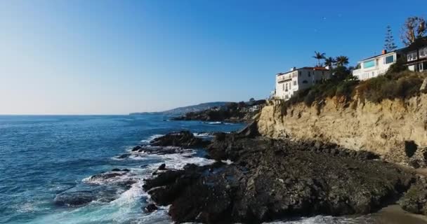 Dron létá poblíž strmého mysu s domy na něm, letecký výstřel na pobřeží Laguna Beach, Kalifornie, USA — Stock video