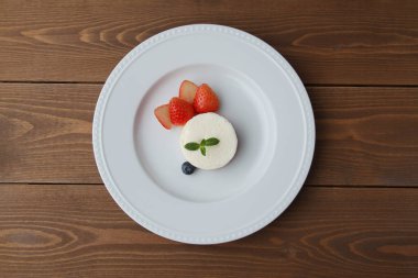 Tabaktaki beyaz şifon peynirli kek ahşap masada izole edilmiş.