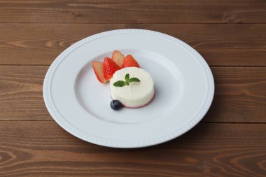 Tabaktaki beyaz şifon peynirli kek ahşap masada izole edilmiş.