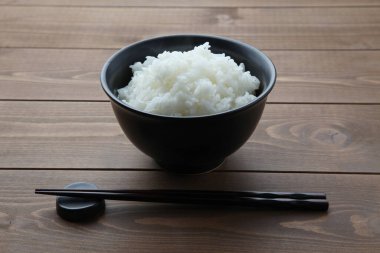 plain white rice in bowl with chopsticks isolated on table