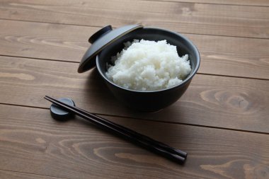 plain white rice in bowl with chopsticks isolated on table