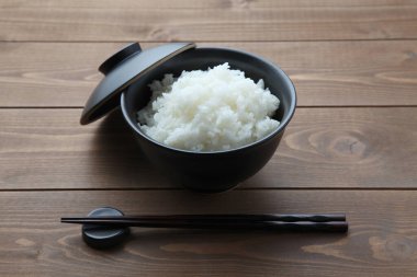 plain white rice in bowl with chopsticks isolated on table