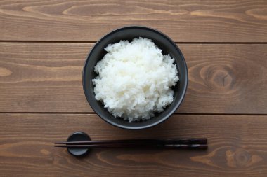 plain white rice in bowl with chopsticks isolated on table
