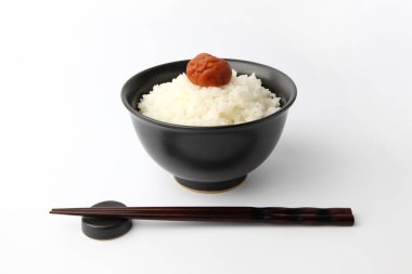 Beyaz arka planda izole edilmiş kase çubuklarıyla tuzlanmış erikli sade pirinç.