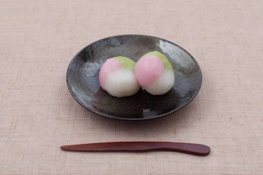 Masa örtüsü üzerinde üç renkli hamur tatlısı Japon pastası.