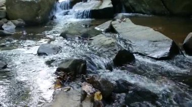 Nehrin aşağısında taşlarla dolu bir şelalenin yanında akan su.