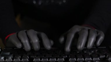 Maskeli Karakter Korsanının eldiven takarak bir bilgisayar klavyesinde daktilo etmesi