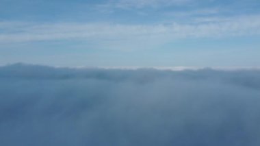 White loose clouds move across the blue sky.