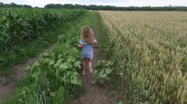 The girl in a sundress runs on a field road