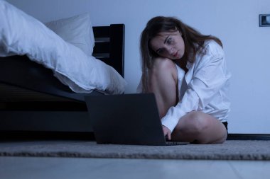 Genç bir kadın geceleri dizüstü bilgisayarla üzgün ve yalnız hissediyor.