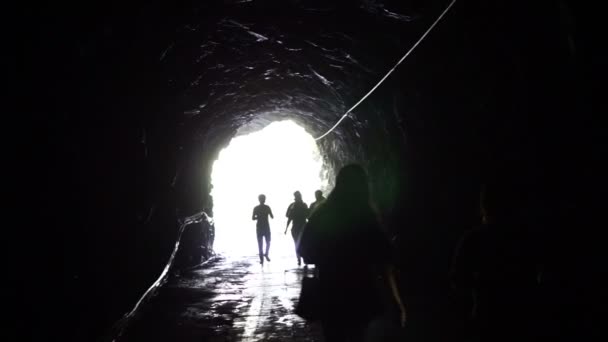 Die Silhouette der Menschen geht durch den dunklen Tunnel in das glühende Ende. Freiheit und Lösungskonzept — Stockvideo