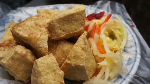 Fried stinky tofu serve on plate with plastic. Famous and iconic fermented tofu of Taiwan — Stock Video