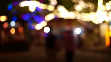 Büyük ağaçlar ve insanlar yapısı altında renkli lambalar Festivali yürüyüş bulanık ışıkları