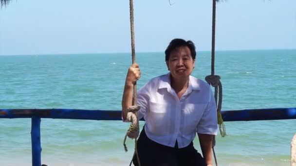 Hermosa mujer asiática mayor relajarse en el columpio en la playa con fondo azul mar — Vídeo de stock