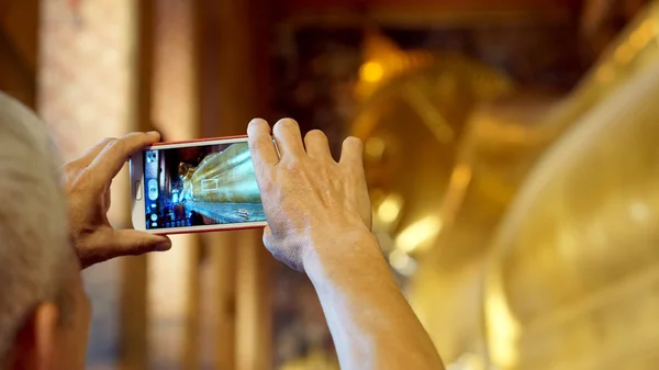 पर्यटक सोते हुए बुद्ध के मंदिर में स्मार्टफ़ोन के साथ फोटो ले रहा है, बैंकॉक थाईलैंड लैंडमार्क — स्टॉक फ़ोटो, इमेज